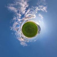 Little planet transformation of spherical panorama 360 degrees. Spherical abstract aerial view in field with awesome beautiful clouds. Curvature of space. photo