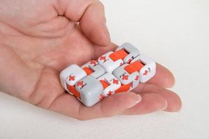 Colorful fingers antistress fidget cube toy in hand on white background. development of fine motor skills of fingers of children photo