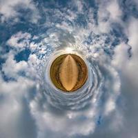 Little planet transformation of spherical panorama 360 degrees. Spherical abstract aerial view in field with awesome beautiful clouds. Curvature of space. photo