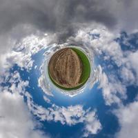 tiny planet in blue sky with beautiful clouds. Transformation of spherical panorama 360 degrees. Spherical abstract aerial view. Curvature of space. photo