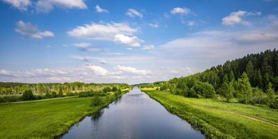 paisaje de un hermoso río ancho o canal en un día soleado con reflejo azul con hermosas nubes en el agua foto