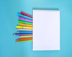 cuaderno de bocetos con lápices y rotuladores sobre una mesa azul. foto