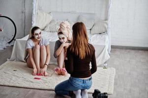 joven fotógrafa disparando en el estudio a dos chicas mientras hacen su propia crema de máscaras. fotógrafo profesional en el trabajo. foto