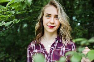 Close-up portrait of a smiling blond girl in tartan shirt in the countryside. photo