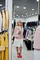 Elegance blonde girl in coat at the store of fur coats and leather jackets. photo
