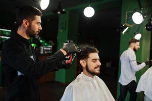 Handsome bearded man at the barbershop, barber at work. photo