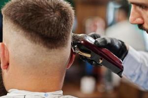 Handsome bearded man at the barbershop, barber at work. Close up nape. photo