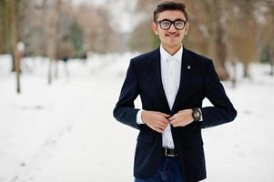 Elegante estudiante indio con traje y gafas posó en el día de invierno al aire libre. foto