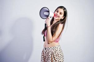 retrato de una hermosa joven en traje de baño y sombrero habla por megáfono en el estudio. foto