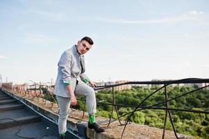 hombre macho con estilo soñador en traje gris y gafas posadas en el techo. foto