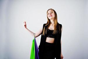 Girl model in black wear with colored shopping bags posed at studio on white background. photo