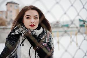 Close up portrait of brunette girl in scarf against cage. photo