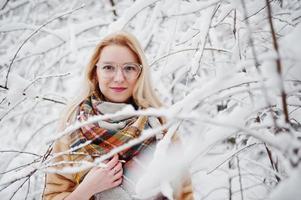 retrato de chica rubia con gafas, abrigo de piel rojo y bufanda en el día de invierno. foto