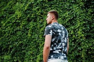 Lifestyle portrait of handsome man posing against greenery wall. photo