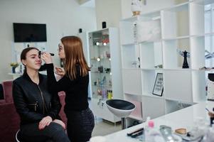 Make up artist work in her beauty visage studio salon. Woman applying by professional make up master. Beauty club concept. photo