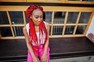 Fashionable african american girl at pink pants and red dreads posed outdoor. photo