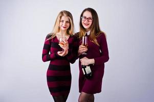 dos amigos atractivos vestidos de púrpura beben vino espumoso o champán en el estudio. foto
