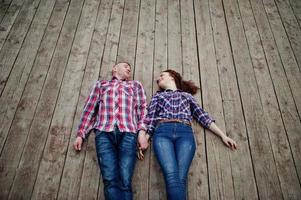 Stylish couple wear on checkered shirt in love together lie on the boards. photo