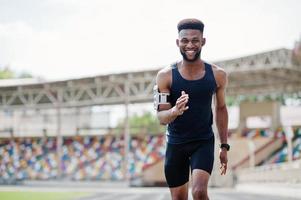 African american male athlete in sportswear racing alone down a running track at stadium. photo