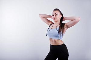 Cheerful attractive young fitness woman in top and black leggings with jump rope isolated over white background. photo