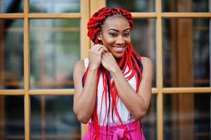 Fashionable african american girl at pink pants and red dreads posed outdoor. photo
