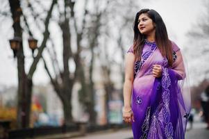 Indian hindu girl at traditional violet saree posed at street. photo