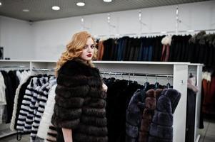 chica rubia de elegancia en abrigo de piel en la tienda de abrigos de piel y chaquetas de cuero. foto