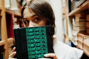 Girl with pigtails in white blouse at old library. photo