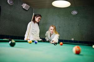 Two sexy girls in white bathrobe play pool billiards. photo