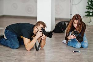 el equipo de dos fotógrafos disparando en el estudio de rodillas. fotógrafo profesional en el trabajo. clase maestra. foto