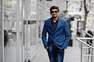 Young indian man on blue suit and sunglasses posed outdoor. photo