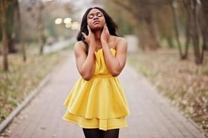 mujer afroamericana con estilo en vestido amarillo posó contra el parque de otoño. foto