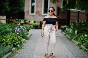 elegante mujer afroamericana en gafas de sol planteadas al aire libre. foto