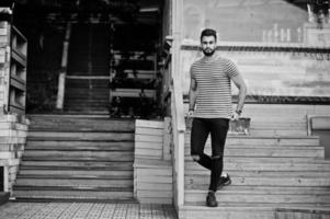 Handsome tall arabian beard man model at stripped shirt posed outdoor. Fashionable arab guy. photo