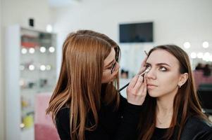 Make up artist work in her beauty visage studio salon. Woman applying by professional make up master. Beauty club concept. photo