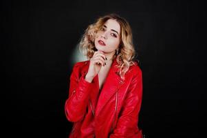 Studio portrait of blonde girl in red leather jacket against black background. photo