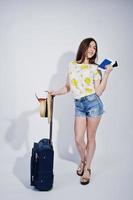 Girl tourist with bag and passport, wear in shirt, shorts and hat with glasses isolated on white. photo