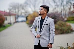 Stylish indian man with bindi on forehead and glasses, wear on suit posed outdoor. photo