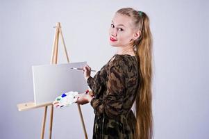 Beautiful woman artist painter with brushes and oil canvas posing in studio isolated on white. photo