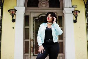 Stylish african american plus size model at streets of city against enter of house. photo