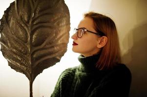 Cheerful young beautiful redhaired woman in glasses, wear on green warm wool sweater,  posed at cafe. photo