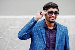 Young indian man on blue suit and sunglasses posed outdoor. photo