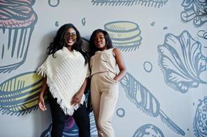 Two stylish african american girls at cafe posed against wall. photo