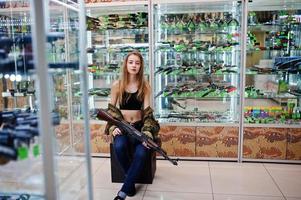 Girl with machine gun at hands on army store shop. photo