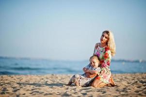 madre e hija hermosa divirtiéndose en la playa. retrato de mujer feliz con linda niña de vacaciones. foto