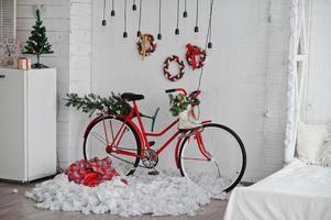 bicicleta de decoración roja con patines de hielo en la decoración navideña en el estudio. foto