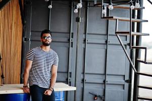 Handsome tall arabian beard man model at stripped shirt posed outdoor. Fashionable arab guy at sunglasses. photo