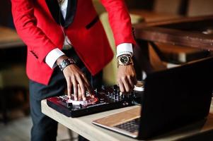 manos de moda hombre afroamericano modelo dj en traje rojo con controlador de dj. foto