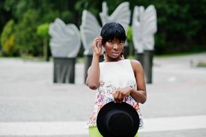 Amazing african american model woman in green pants and black hat posed at park. photo