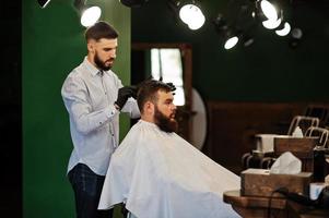 Handsome bearded man at the barbershop, barber at work. photo